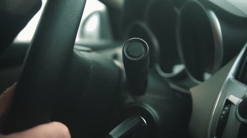 Young Man Driving a Car and Turns on the Wipers