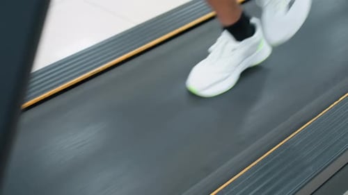 Ansicht eines Athleten, der auf einem Laufband läuft, von oben nach unten mit verschwommenem Fitness-Hintergrund