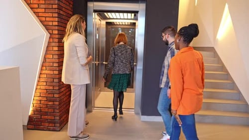 Group of friends eagerly waiting for the elevator in a modern building