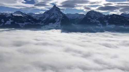 aerial - churfirsten summits emerging sharply from a glowing cloud ocean
