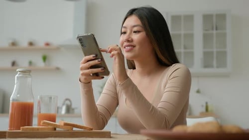 Young Woman Using Phone at Kitchen Table