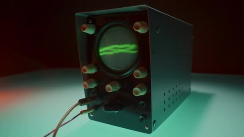 Osciloscópio com cabos conectados exibindo forma de onda de alta amplitude