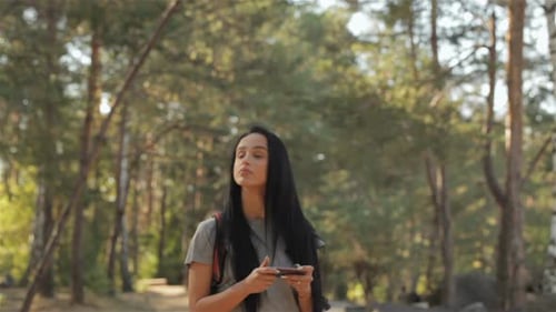 Woman Using Phone in a Sunny Forest
