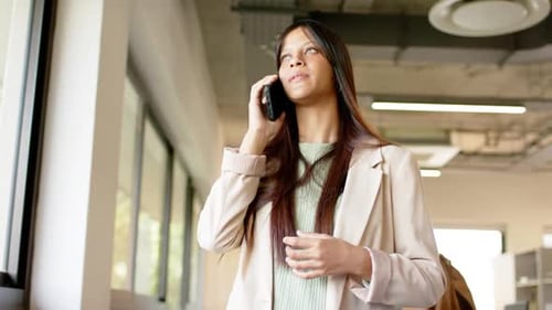 Glückliche biraciale Gelegenheitsgeschäftsfrau, die im Büro auf dem Smartphone spricht, Zeitlupe