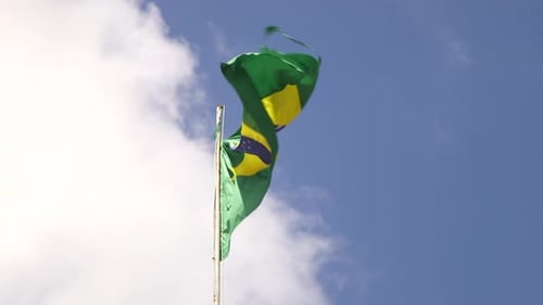 Brazilian Flag Waving Against Blue Sky and Clouds