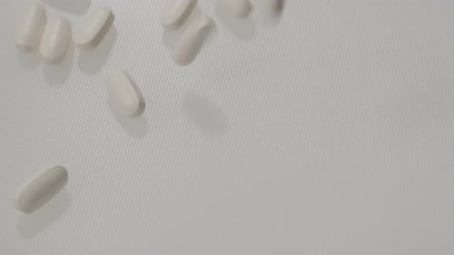 White Pills Falling in Slow Motion