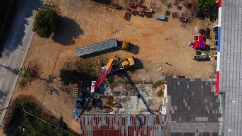 Mobile crane stands waiting to lift steel at a warehouse. Crane operators and mobile cranes