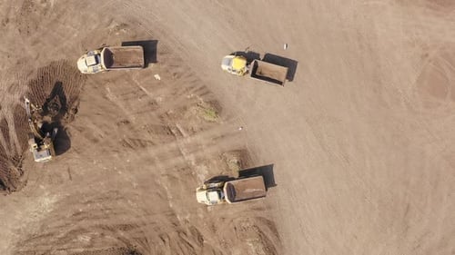 Excavator And Trucks Working on Dirt Site