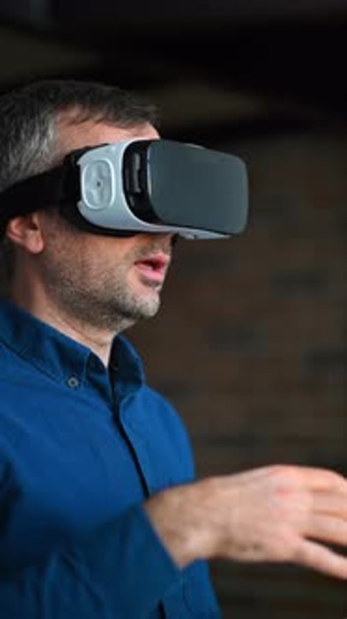Man gesturing while using a Virtual Reality headset in an office. Vertical