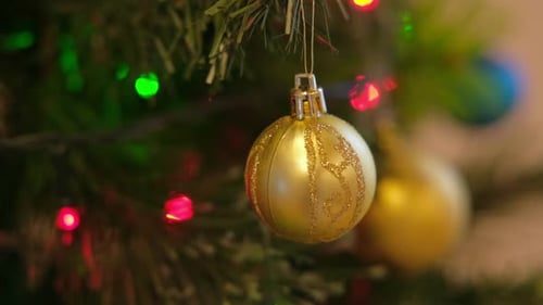 Golden Christmas Ornament Hanging on Tree with Lights