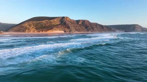 Cliff-lined beach with rolling surf waves