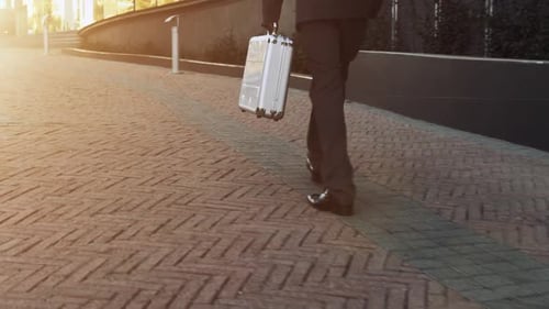 Businessman Walking with Silver Briefcase in Golden Light