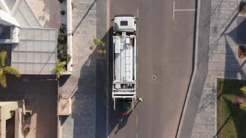 Municipal garbage truck at work, loading green trash cans.