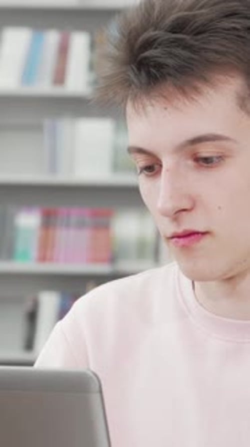 Cheerful Young Male Student Studying with Enthusiasm in a Vibrant Library