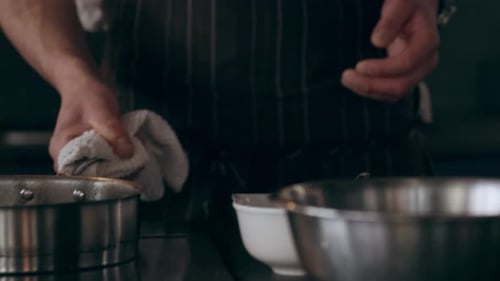 Chef Prepares Food with Stainless Steel Cookware Indoors