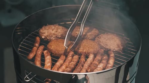Juicy Beef Burgers and Sausages Sizzling on Outdoor Charcoal Grill
