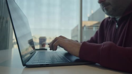 Freelancer, der Code im Coworking Space auf der Laptop-Tastatur eingibt, Nahaufnahme