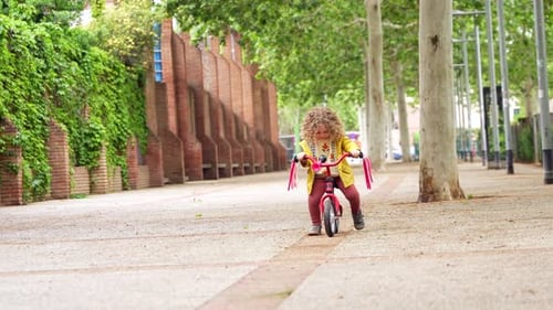 Happy Girl Riding a Pink Bicycle in the Park