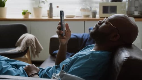 Man Using Mobile Phone on Sofa in Apartment