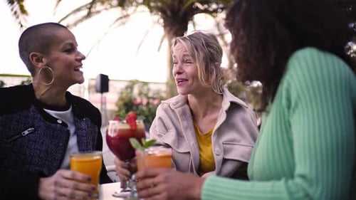 Three Cheerful Mature Women Having Drinks Outside in a Terrace Toasting with Cocktails or Mocktails