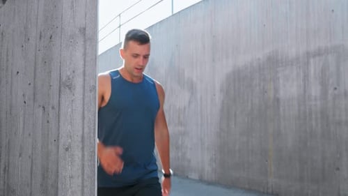 Young man running along city street checking smart watch fitness concept