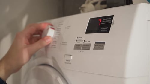 Hand Adjusts Washing Machine Settings