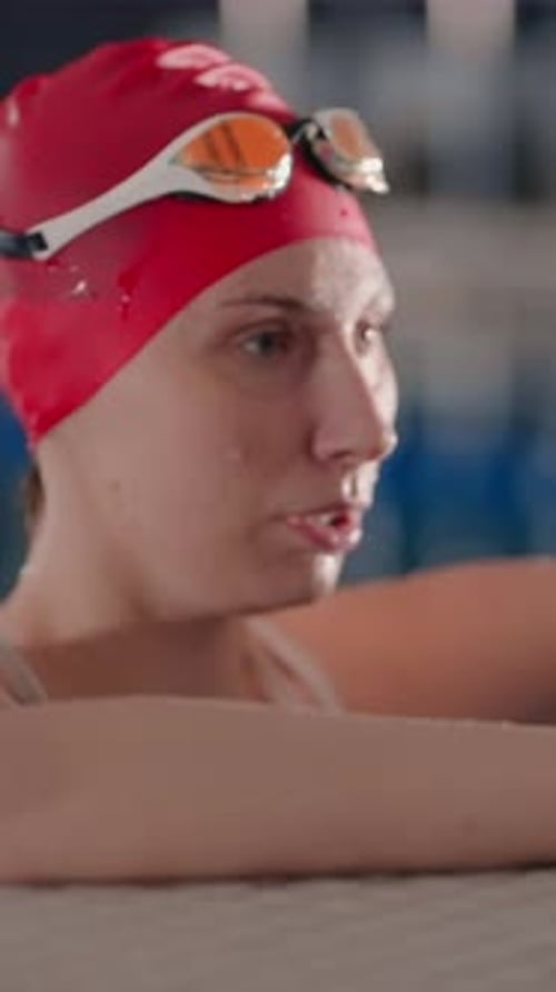 Focused Swimmer in Red Cap Resting at Pool Edge Catching Breath with Eyes Closed Between Intense