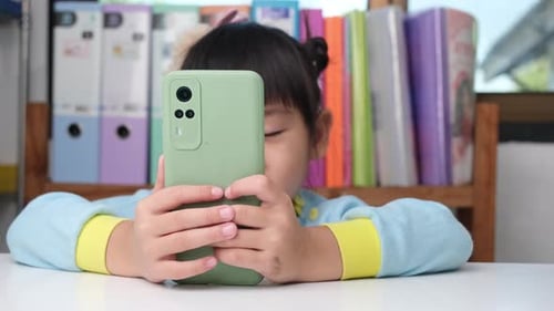 Child Holding Mobile Phone Indoors