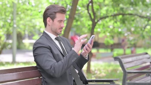 Man in Suit Using Smartphone on Park Bench