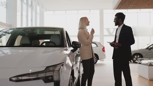 Happy Woman Receiving New Car Keys from Salesman