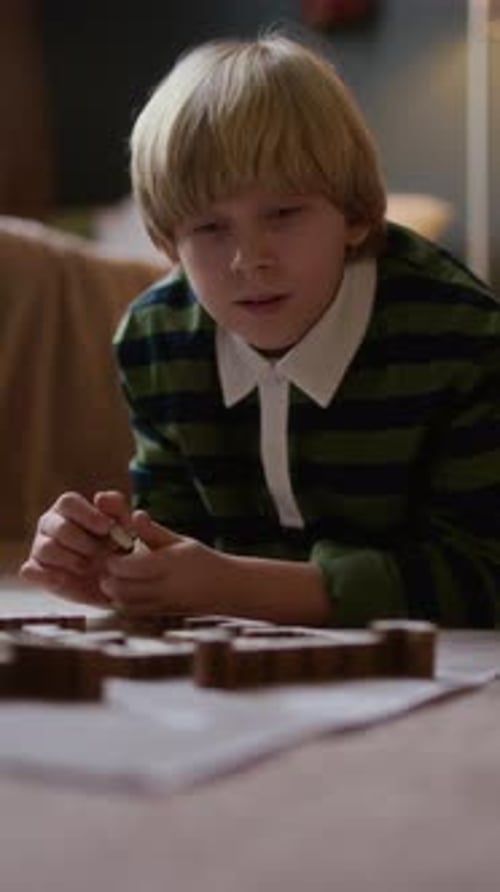 Niño habilidoso que se concentra en resolver un rompecabezas de madera en el piso