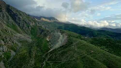 The mountains are covered in green trees and the sky is cloudy