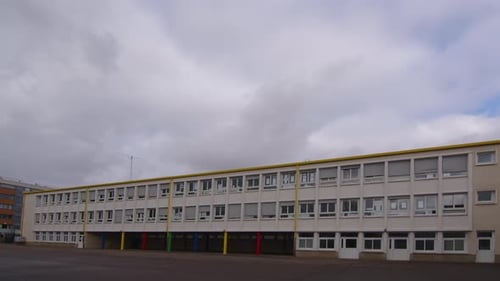 Aufnahmen einer Schulfassade Weitwinkelaufnahmen rahmen die Bewegung von Wolken über dem Dach eines modernen Gebäudes ein