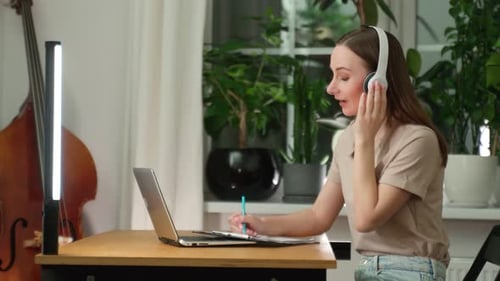 A Female Musician Listens to Music While Composing a Song in a Music Studio