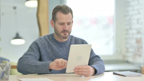 Man with Tablet Cheers in Bright Office Setting