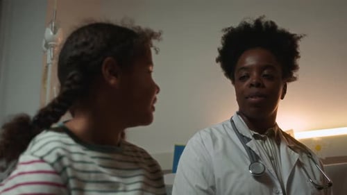 Caring African American Doctor Talking to Little Black Patient in Hospital