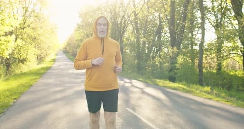 Old Caucasian Senior Handsome Pensioner Man Having Workout Running Outside on Street on Sunrise