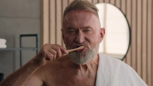Senior Man Brushing Teeth in Modern Bathroom