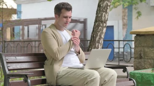 Man Uses Laptop on Park Bench, Wrist Pain