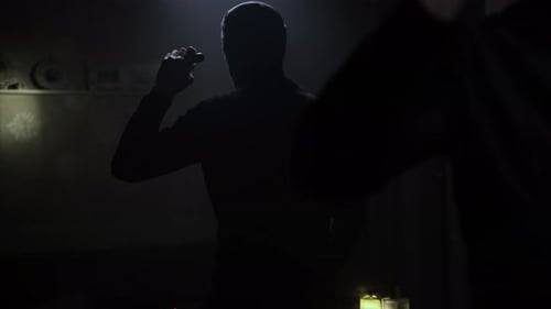 Figures in Balaclavas with Flashlights in Dark Interior