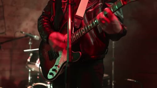 Man Playing Electric Guitar Under Red Stage Lights
