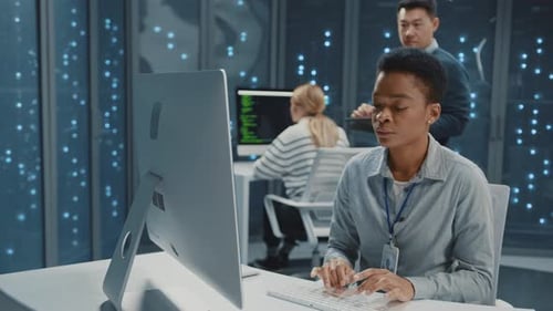 Data Center Afroamerican Young Woman Using Computer Desktop and Cooperating with IT Administrator