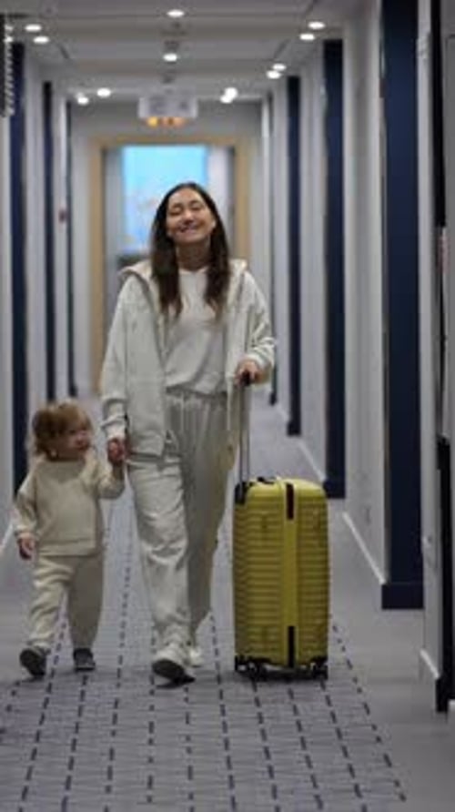 Mère souriante marchant vers la caméra, voyage dans un couloir lumineux, approche avec un tout-petit à côté, jaune