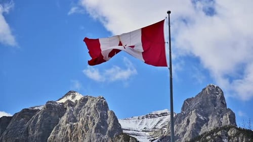 Canadian Flag Waving Against Snowy Mountain Backdrop