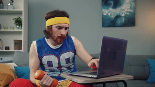 Engagierter Heimtraining-Enthusiast, ausgestattet mit einem Laptop und einer Hantel zum Training