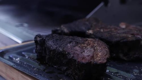 Thick juicy charcoal steak smoking on outdoor grill, close up shallow depth of field