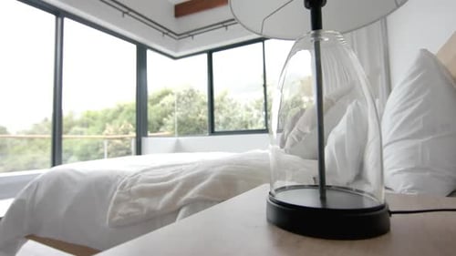 Interior of domestic bedroom with double bed and corner windows over garden, copy space, slow motion