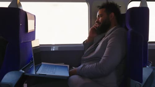 Un homme d'affaires concentré travaille assidûment sur son ordinateur portable tout en faisant la navette en train