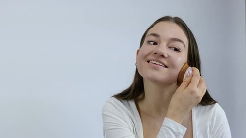 Woman Applies Makeup with Brush in Studio