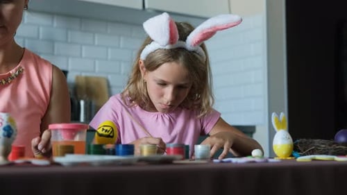 Kleines Mädchen mit Mutter beim Basteln von Osterdekorationen